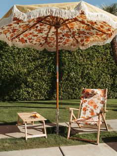 two lawn chairs under an umbrella in the grass