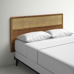 a bed with white pillows and a headboard made out of wicker, on a light colored floor