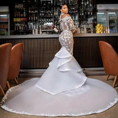 a woman standing in front of a bar wearing a white dress with ruffles