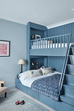 a bedroom with blue walls and stairs leading up to the loft bed, which has a ladder