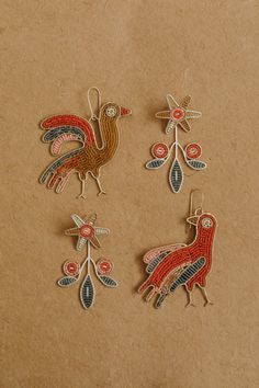 three embroidered bird ornaments sitting on top of a piece of brown paper next to each other