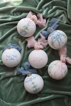 christmas ornaments with numbers and bows on them laying on a green cloth covered bed sheet