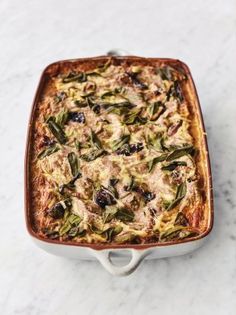 a casserole dish filled with food on top of a marble countertop next to a spoon