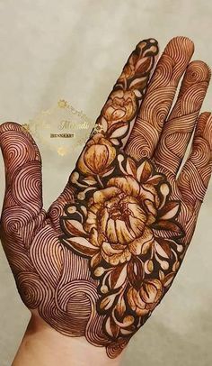 a person's hand with hennap and flowers painted on the top of it