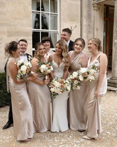 a group of people standing next to each other in front of a building with flowers