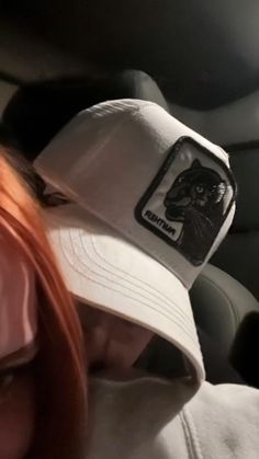 a woman wearing a white hat with a black cat sticker on the front of it