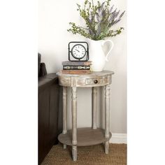 a small table with a clock on it and some flowers in a vase next to it