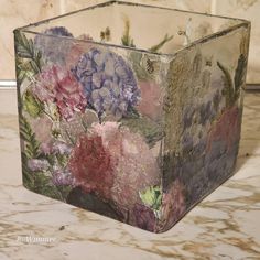 a vase with flowers painted on it sitting on a marble counter top next to a tile wall