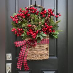 a basket filled with red berries and pine cones hangs on the front door's black door