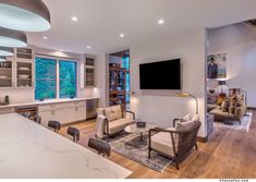 a living room filled with furniture and a flat screen tv mounted to the side of a wall