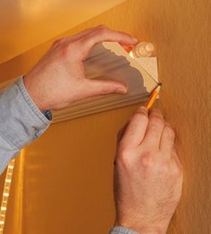 a man is holding a pencil and writing on a piece of paper that has been taped to the wall