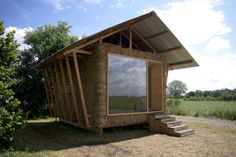 a small house made out of hay sitting in the middle of a field with stairs leading up to it