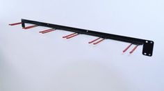 a metal rack with red wires hanging from it's sides on a white wall