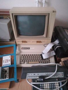 an old computer sitting on top of a wooden desk next to other electronic devices and keyboards