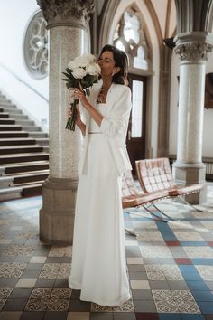 a woman in a long white dress holding flowers