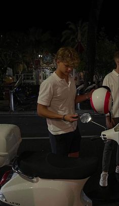 two men standing next to each other near a motor scooter with a ball on it