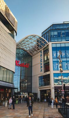 people are walking around in front of the westland bank building and shopping center on a sunny day