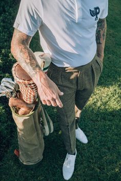 a man with tattoos is holding a basket full of golf clubs and balls in his hands