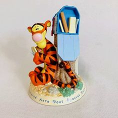 a winnie the pooh figurine sitting next to a mailbox with books on it