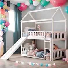 a white bunk bed with a slide in front of it and balloons around the room