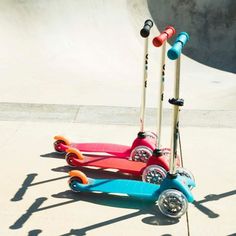 two colorful scooters parked next to each other in front of a skate park