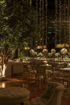 the tables and chairs are all set up for an event with white flowers hanging from the ceiling