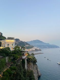 an aerial view of the ocean with boats in the water and houses on the cliff