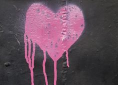 a pink heart painted on the side of a wall with water dripping down it's sides