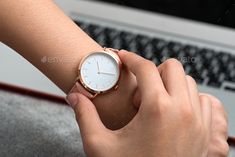 a woman holding onto her watch while sitting in front of a laptop - stock photo - images