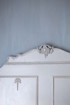 an old white bed with ornate headboard against a blue wall in a bedroom or living room