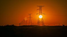 the sun is setting behind some power lines