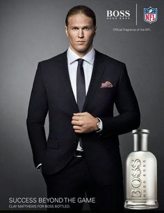 a man in a suit and tie standing next to a bottle of boss eau