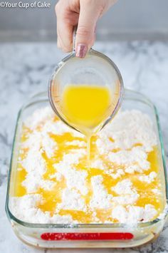 someone is pouring orange juice into the batter in a glass bowl with sugar on top