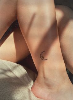 a woman's legs with a small crescent tattoo on her left ankle and right leg