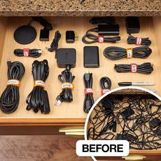 an open drawer filled with electronic devices and cords on top of a wooden countertop