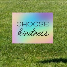 a sign that says choose kindness on it in the middle of green grass with a blue and pink background