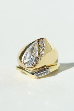 a yellow gold ring with two pear shaped diamonds on the top and side, set against a white background