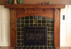 a fireplace in a living room with tile and wooden mantels on either side