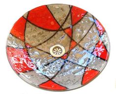 a glass sink with red, grey and white designs on it's bowl top