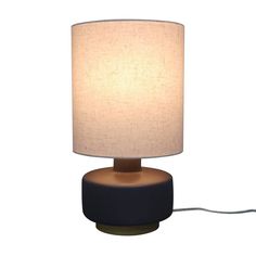 a table lamp with a white shade on it and a cord plugged into the base