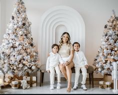 a woman and two children sitting in front of christmas trees