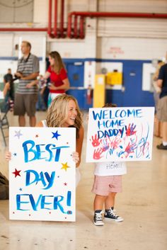 two children holding signs in a gym with people standing around and looking at the camera