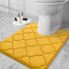 a bathroom with a toilet and yellow rugs on the floor in front of it