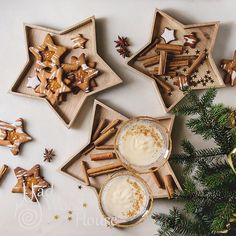 three small wooden trays filled with cookies and drink next to christmas decorations on a white surface