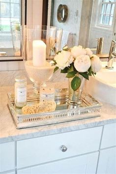 a tray with flowers and candles on top of a bathroom counter next to a sink