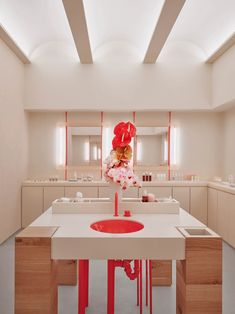 a bathroom with a sink, mirror and red vase on top of it's counter