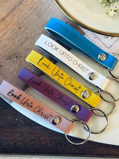 four different colored keychains with names on them sitting next to a flower vase