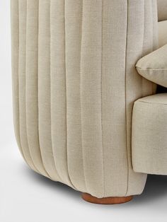 an upholstered couch with wooden legs and pleated fabric on the armrests