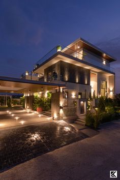 a modern house lit up at night with lights on the front and side of it