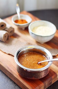 a wooden cutting board topped with bowls of food